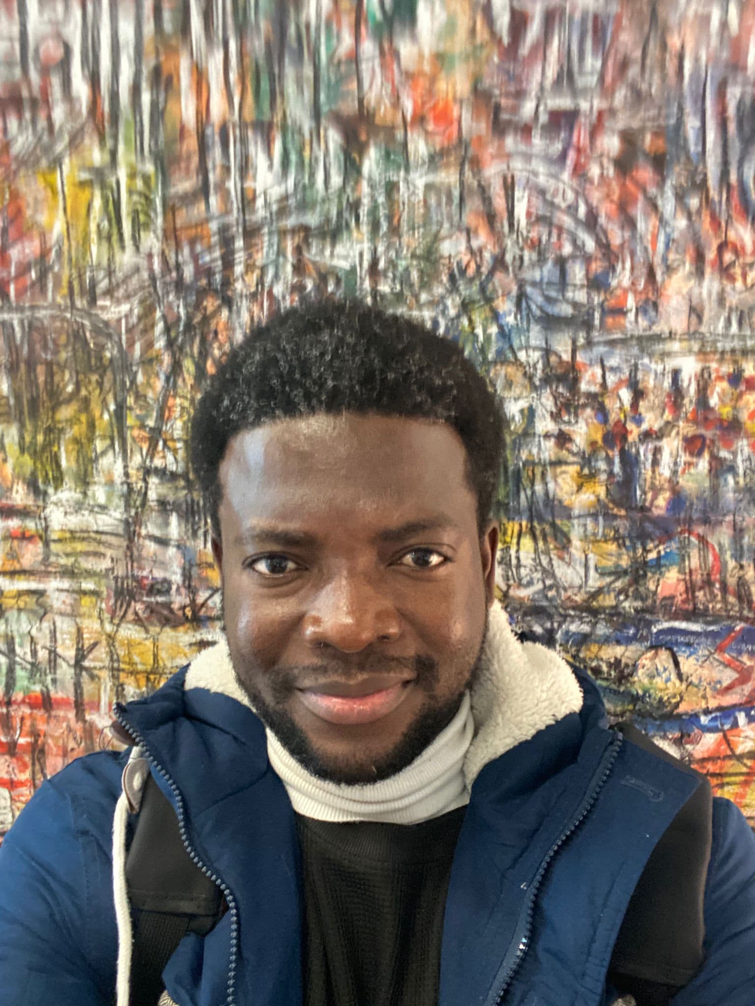 Theodore Aware smiling in front of colourful artwork
